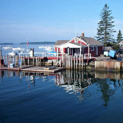 Small red house sits in a pier on a harbor in calm water.