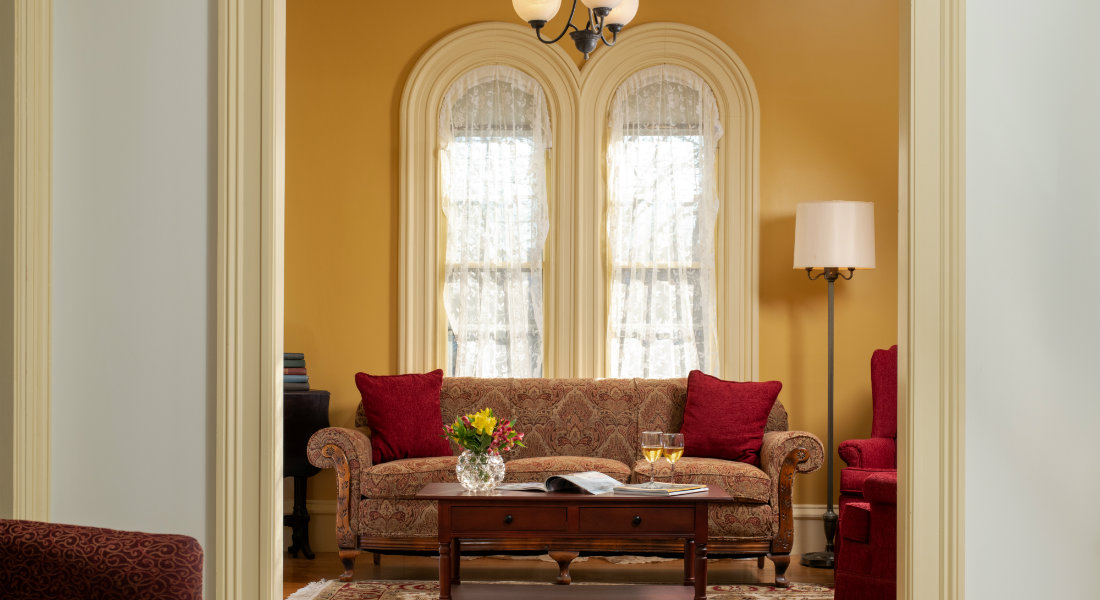 View from the hallway into a room with unique rounded windows and a floral sofa with a table in front.