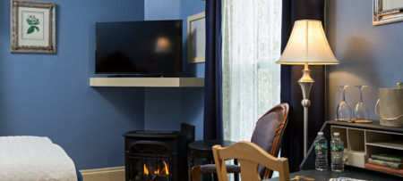 A desk with water, an ice bucket and wine glasses in a room with blue walls and dark blue drapes.