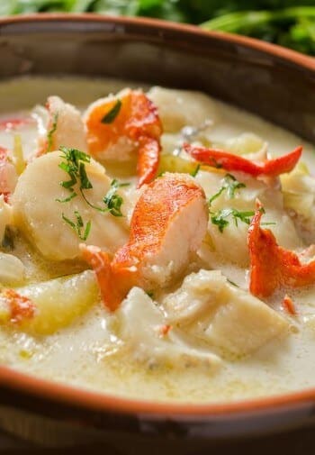 A crockery bowl of lobster chunks in a rich creamy broth.